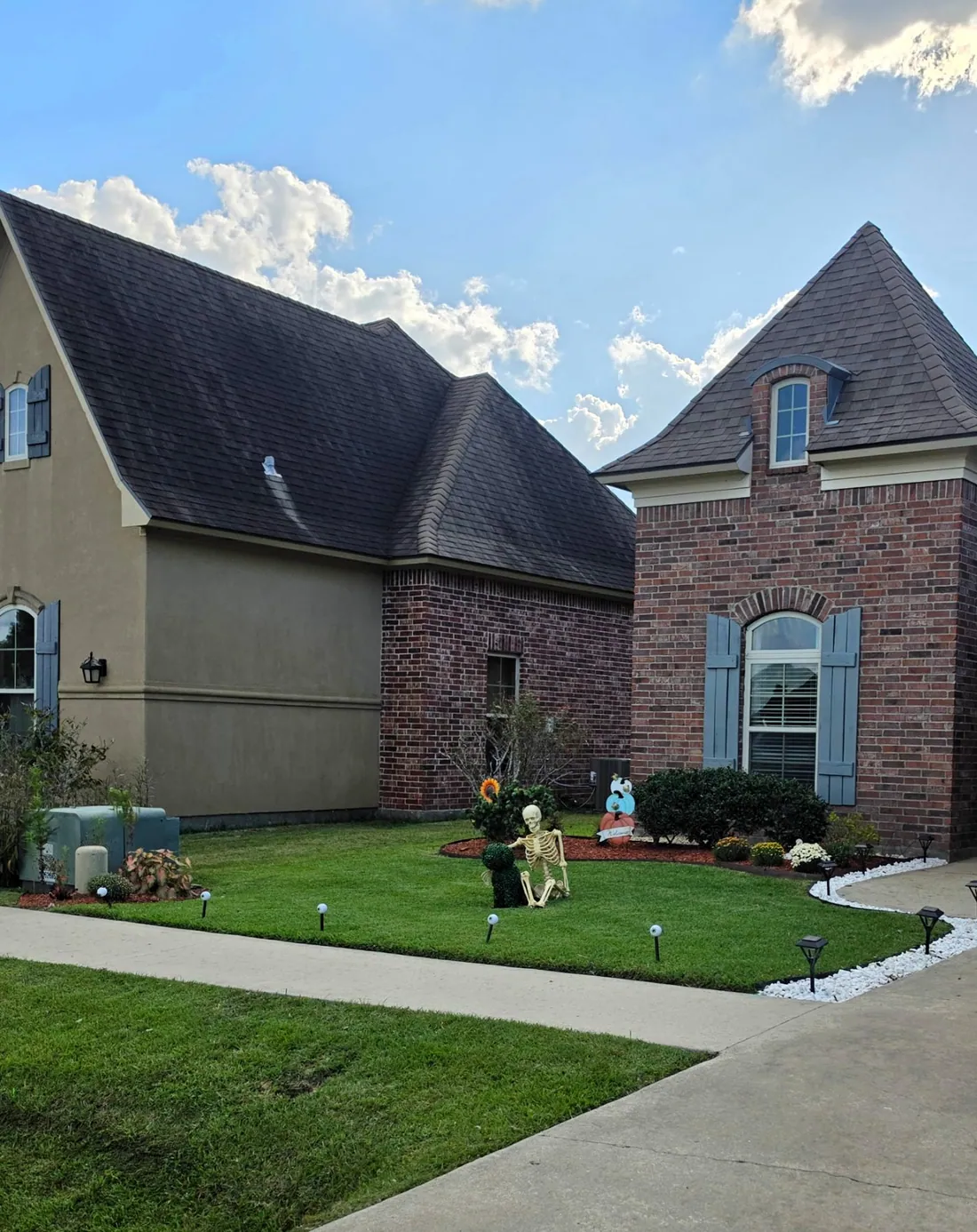 Freshly mowed lawn with crisp edges along the sidewalk and driveway and a clean rock-bordered bed, a recent SSB Lawn Services job in the Broussard area